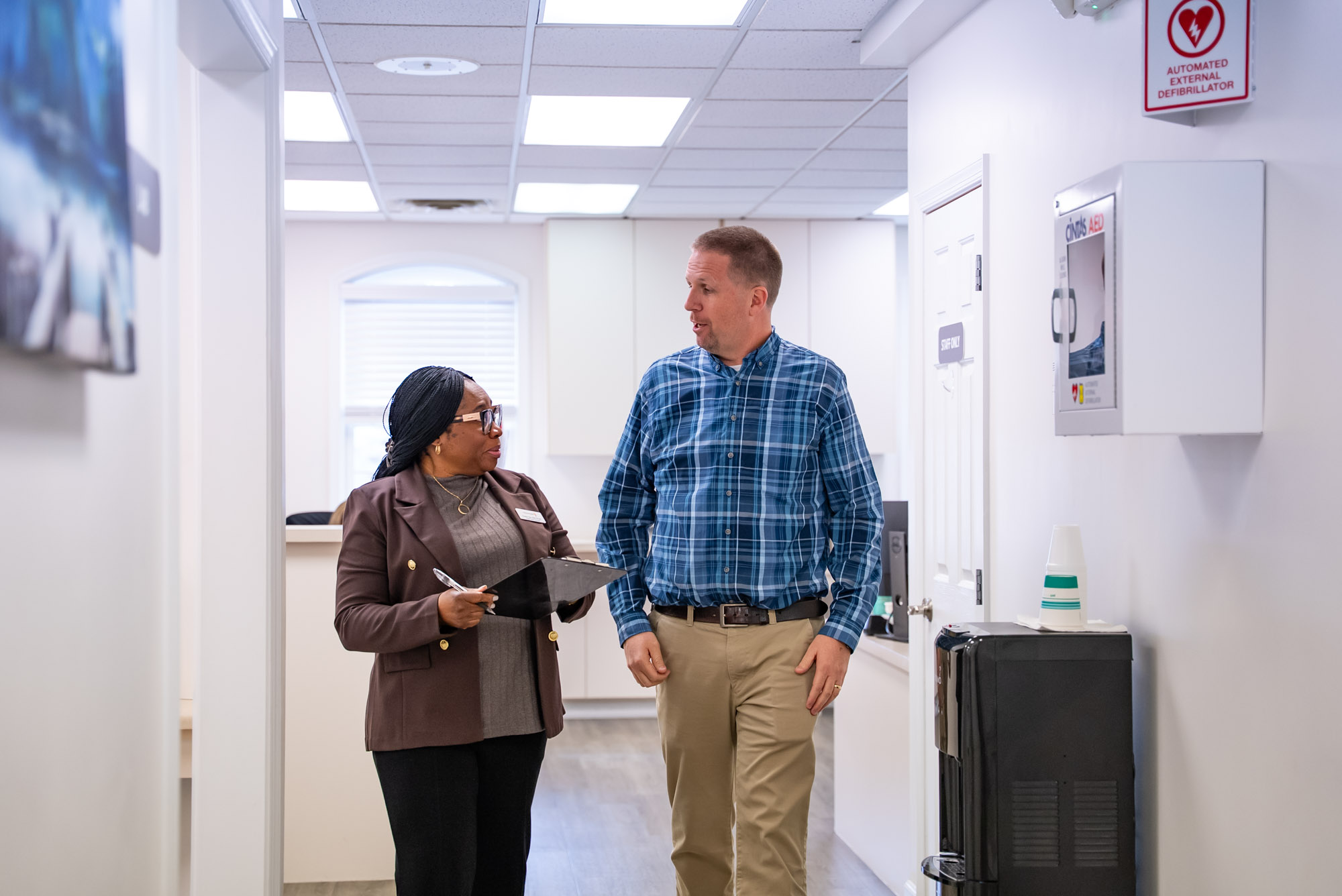 a man and woman walking and talking in a doctors office
