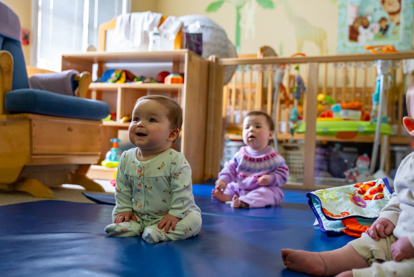 two young babies sitting and smiling in a nursery room