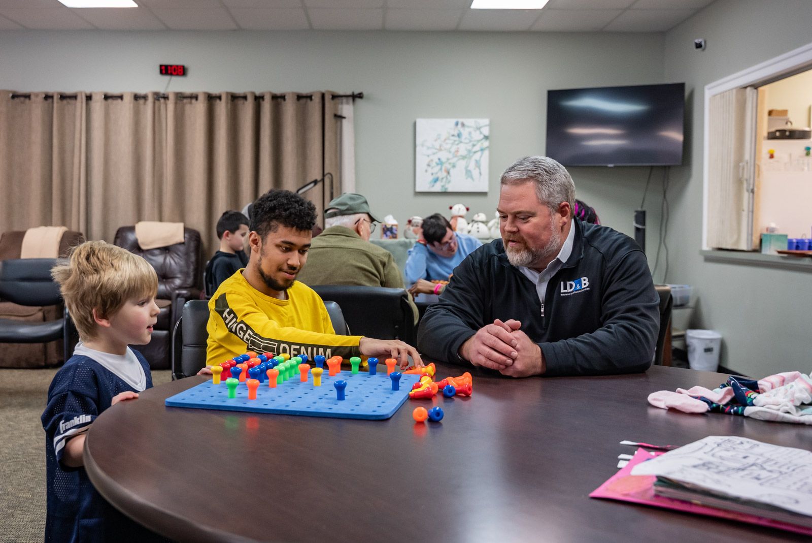 older gentleman sitting and playing a board game with a young boy and teenager